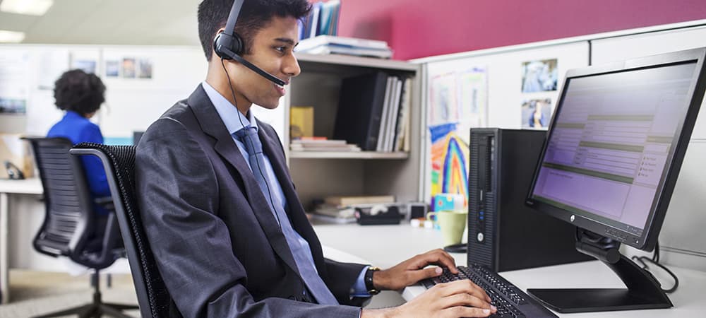 Worker using the HP ProDesk 600 SFF with the HP ProDisplay P221 while sitting at desk wearing headphones